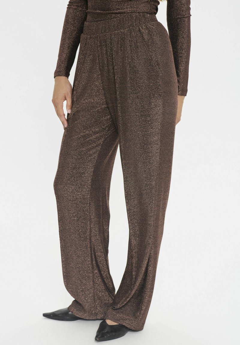 Braune, glitzernde weite Hosen aus einem weichen Material mit einem elastischen Bund. Kombiniert mit schwarzen spitzen Ballerinas.