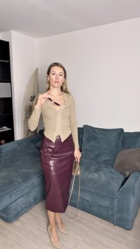 Beige langermet topp med blonder, burgunder følskinn blyantskjørt, beige hæler og liten veske. Teksturert teal sofa i bakgrunnen.