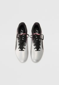 Silver soccer shoes with a textured upper, black laces, and pink accents. Features logo on tongue and a sleek design.