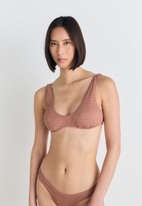 Hnedý textúrovaný bikini s dizajnom na krku a širokými ramienkami. Tkanina má jemný cik-cak vzor a bezšvové spracovanie.