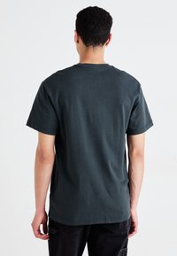 T-shirt grigio scuro a maniche corte con colletto rotondo, realizzato in morbido cotone, caratterizzato da un design semplice e una vestibilità comoda.