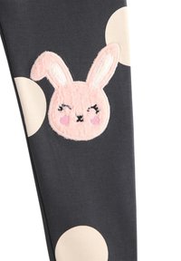 Leggings hebben een donkergrijze stof met een zachte, tekstuurvolle roze konijnapplicatie en crèmekleurige stippen. Het ontwerp heeft afgeronde randen bij de tailleband.