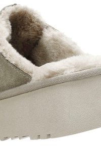 Scarpa slip-on in suede grigio foderata in morbido pellicciotto beige, con una suola piatta bianca testurizzata e cuciture visibili lungo i bordi.