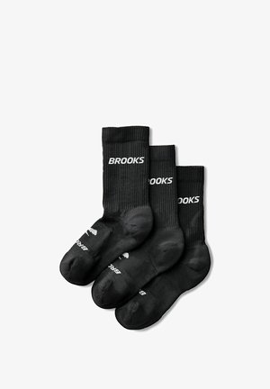 Tre par sorte crew-sokker med ribbet tekstur og hvid "BROOKS" logo på læg og fod, vist overlappende på hvid baggrund.