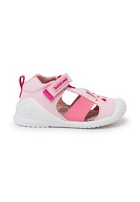 Pink fabric shoe with a closed toe and cutout design, adjustable velcro strap, white rubber sole, and colorful embroidered accents.