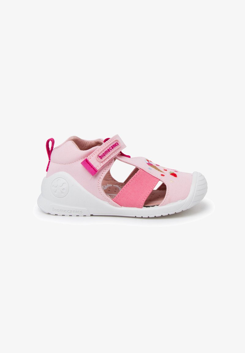 Pink fabric shoe with a closed toe and cutout design, adjustable velcro strap, white rubber sole, and colorful embroidered accents.