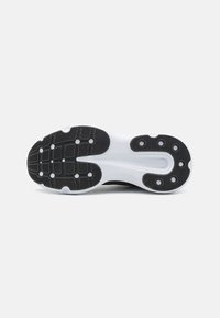 Suela de zapato atlético negro con entresuela blanca, que presenta patrones de agarre de goma texturizados y puntos de tracción circulares.