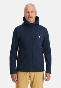 Marineblauwe zip-up hoodie van textuurstof, met een verstelbare capuchon en een borstzak met een contrasterend paneel en logo.