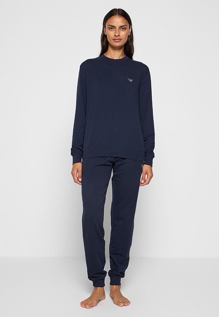 Sweatshirt en coton bleu marine et pantalon assorti, avec un col rond, des manches longues et un petit logo sur la poitrine. Texture lisse.