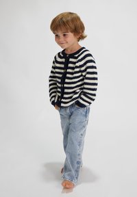 Gestreifter Strickcardigan in Marineblau und Creme, mit rundem Halsausschnitt und Knopfverschluss, kombiniert mit hellblauen Jeans.