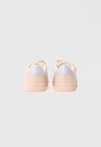 Ροζ αθλητικά παπούτσια με λείο δερμάτινο φινίρισμα, που διαθέτουν ένα ανοιχτό μωβ τόνο στη φτέρνα, στρογγυλεμένο σχήμα και μαλακή, υφασμάτινη επένδυση.