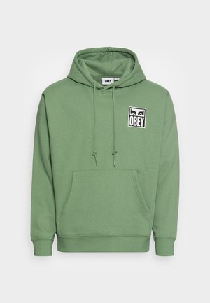 Zielona bluza z kapturem, kieszenią typu kangur i regulowanym sznurkiem w kapturze oraz czarno-białym logo "OBEY" na lewej stronie klatki piersiowej.