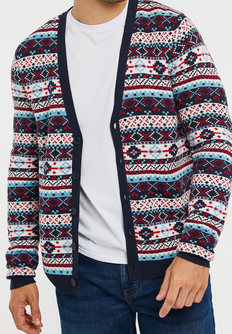 Knitted cardigan in multicolor patterns of red, blue, and white. Features a navy blue trim and front buttons, made of soft material.