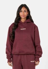 Bordeaux hoodie met een voorzak en een logo-ontwerp in lichtbeige. Gemaakt van zacht materiaal met een relaxte pasvorm en geribde manchetten.