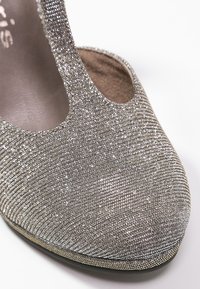 Scarpa col tacco alto, argentata e luccicante, con punta arrotondata, tessuto texturizzato e design con ritagli sui lati, dotata di un interno imbottito.