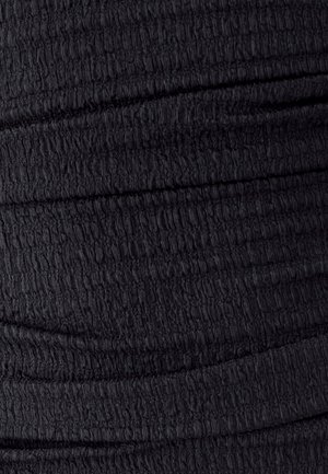 Nahaufnahme eines schwarzen, strukturierten Stoffes mit horizontalen, erhöhten Rillen und leichten Falten.