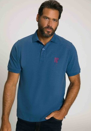 Blå polo skjorte lavet af tekstureret stof, med krave, to knapper ved halsen og et rødt broderet logo på brystet.