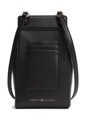 Czarna skórzana torebka na ramię z przednimi przegródkami na karty, regulowanym paskiem oraz złotym logo Tommy Hilfiger na dole pośrodku.