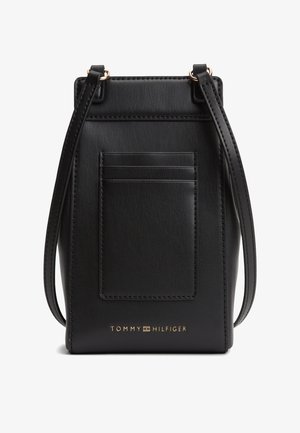 Borsa a tracolla in pelle nera con fessure porta carte frontali, tracolla regolabile e logo Tommy Hilfiger dorato al centro in basso.