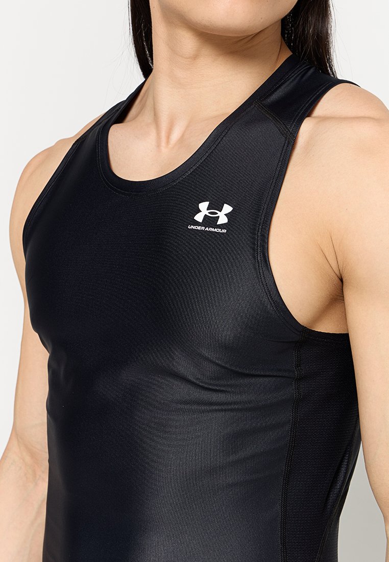 Primo piano di una persona che indossa una maglietta sportiva senza maniche nera attillata di Under Armour, che mostra il torace superiore e le spalle.