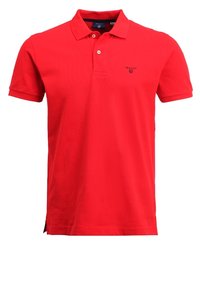 Rød polo shirt lavet af bomuld med klassisk krave, korte ærmer, sideslids og et lille logo på brystet. Glat tekstur.
