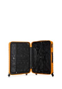 Valise orange rigide avec un intérieur noir à rayures diagonales et des sangles croisées pour sécuriser son contenu. Quatre roulettes multidirectionnelles.