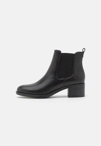 Bottine en cuir noir avec panneaux latéraux élastiques, bout arrondi et un talon carré texturé. Finition lisse et détails de design minimalistes.
