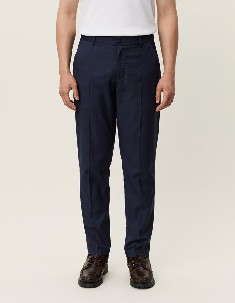 Laivastonsiniset housut, joissa on suora lahkeiden muotoilu, valmistettu sileästä kankaasta. Ominaisuuksiin kuuluu yksittäinen nappisulku ja sivutaskut. Yhdistetty tummiin kenkiin.