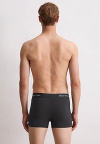 Bóxer negro con tela suave y cintura elástica que lleva el nombre de la marca "Marc O’Polo" en texto blanco.