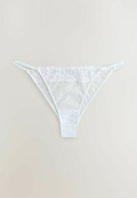 String en dentelle blanche avec bordure en dentelle florale et bretelles latérales réglables sur un fond clair.