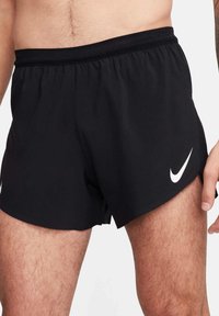 Shorts de course noirs en tissu léger avec une ceinture élastique et des panneaux latéraux en mesh, arborant un logo Nike blanc en bas.