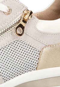 Zapatilla gris claro con tejido texturizado, detalles en hardware dorado y suela de goma blanca, con un distintivo detalle de malla en los laterales.
