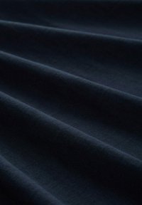 Tessuto nero scuro con una texture liscia, presenta leggere ondulazioni e pieghe. Il materiale appare morbido e leggermente elastico.