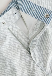 Lightly patterned shorts with a geometric design in shades of blue and gray. Features a striped waistband and zippered pocket.