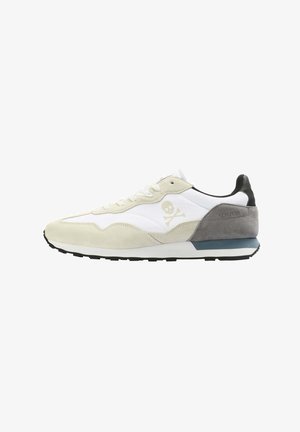 Laufschuhe aus beigem Wildleder und weißem Stoff, mit einem schwarzen Fersenelement und einer blauen Zwischensohle. Totenkopf-Logo seitlich angebracht.