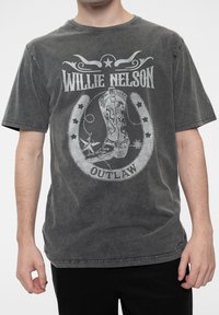 Charcoal gray cotton t-shirt featuring a graphic design with "Willie Nelson" and "Outlaw" text, cowboy boot, and star accents.