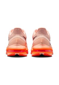 Par de zapatillas deportivas en tonos rosa claro y naranja vistas desde la parte trasera, mostrando las suelas texturizadas y los logotipos de Nike en los laterales.