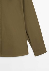 Olivgrünes Langarmhemd mit glatter Textur, durchgehender Knopfleiste und abgerundetem Saum, ausgestattet mit taillierten Manschetten und einem minimalistischen Design.