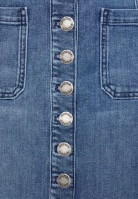 Denimklänning med knäppning fram, sex silvermetallknappar prydda med "PINKO" och två sidofickor. Ljusblå tvätt, strukturerad tyg.