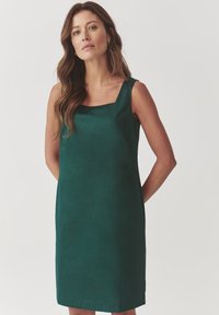 Green sleeveless dress with a squared neckline, made from smooth fabric. Simple, straight silhouette reaches mid-thigh. No notable patterns.