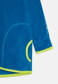 Fleece-Oberteil in leuchtendem Blau mit kontrastierendem neongrünem Saum. Verfügt über einen abgerundeten Saum, genähte Nähte und ein geschwungenes Taschendesign.