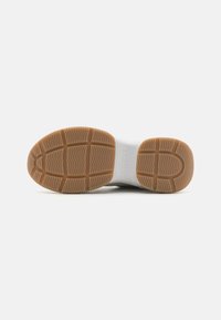 Semelle de sneaker blanche avec une semelle en caoutchouc translucide, dotée d'un motif de relief pour une meilleure adhérence et portant le nom de la marque en relief sur le côté.