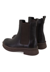 Zwarte leren Chelsea boots met elastische panelen, een gestructureerde bruine zool, een ronde neus en aantrek-lussen aan de achterkant voor gemakkelijk aan- en uittrekken.