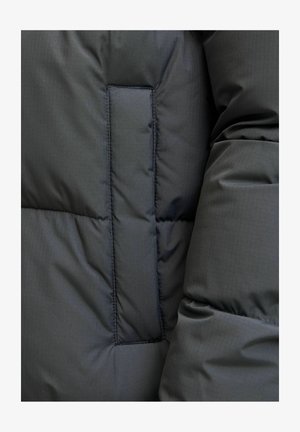 Giacca a vento grigia scura con finitura liscia e opaca. Presenta imbottitura trapuntata e una tasca nascosta sulla manica. Realizzata in materiale leggero.