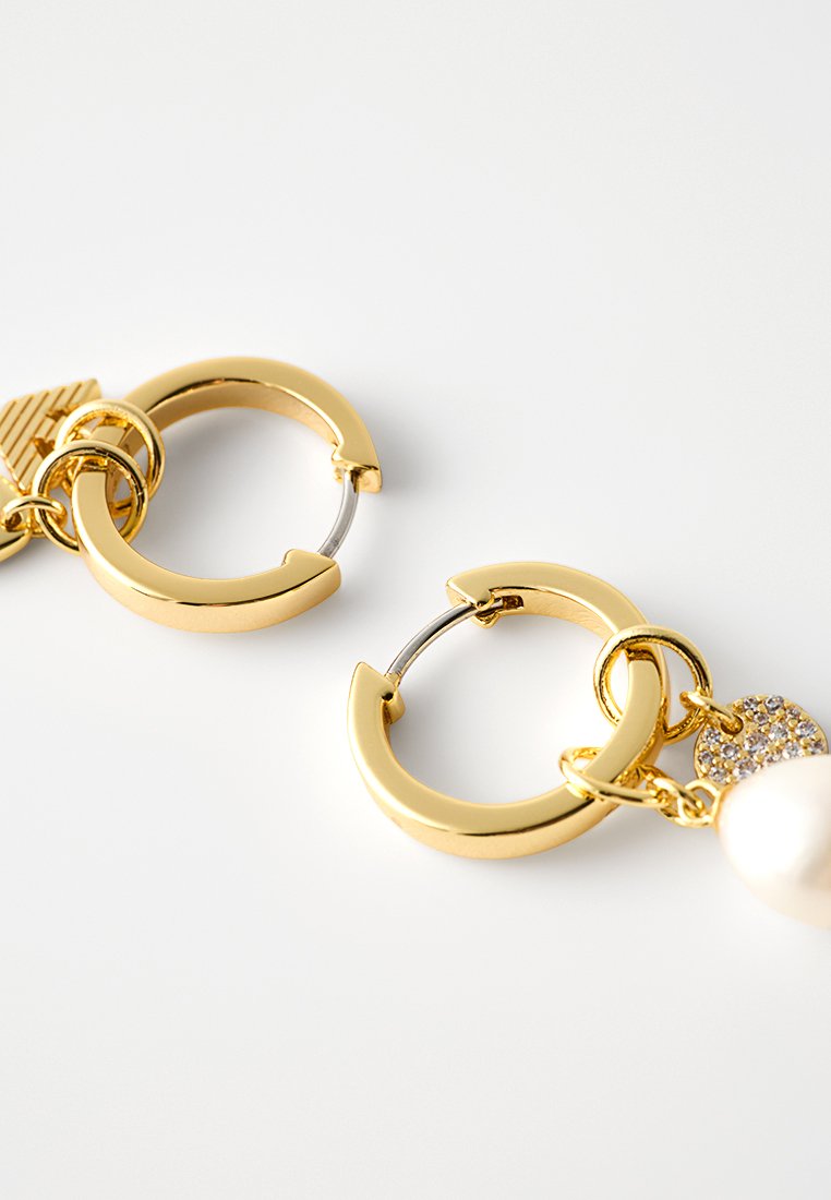 Złote kolczyki na kółkach mają teksturowany charms, akcent perłowy oraz okrągły kształt z małym detalem gemu.