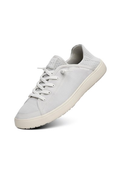 White canvas sneaker with round toe, lace-up design, padded collar, and rubber sole. Features a textured surface and subtle branding.