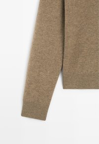 Maglione marrone lavorato a maglia con orlo e polsini a coste, dalla consistenza morbida e dal design aderente. Il tessuto sembra caldo e resistente.