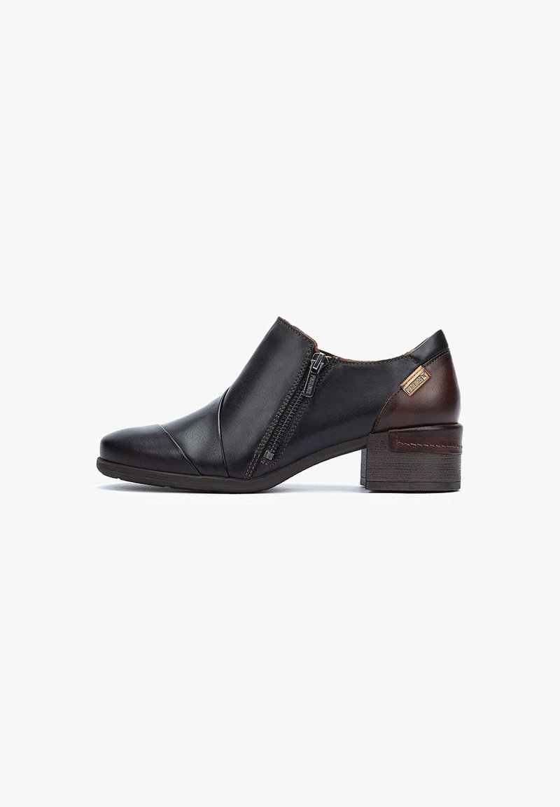 Chaussure en cuir noir avec fermeture éclair sur le côté, à bout rond et à petit talon marron. Présente une texture lisse avec des détails de couture subtils.