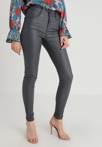 Jeans ajustados grises hechos de material elástico con una textura suave, que presentan una cintura alta y un diseño minimalista. Destacan por su corte ajustado.