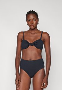 Juodas raukšlėtas bikini rinkinys, sudarytas iš mazgo dizaino bandeau viršaus ir aukštu liemeniu apatinės dalies. Lygus paviršius, reguliuojamos petnešos ir be siūlių kraštai.